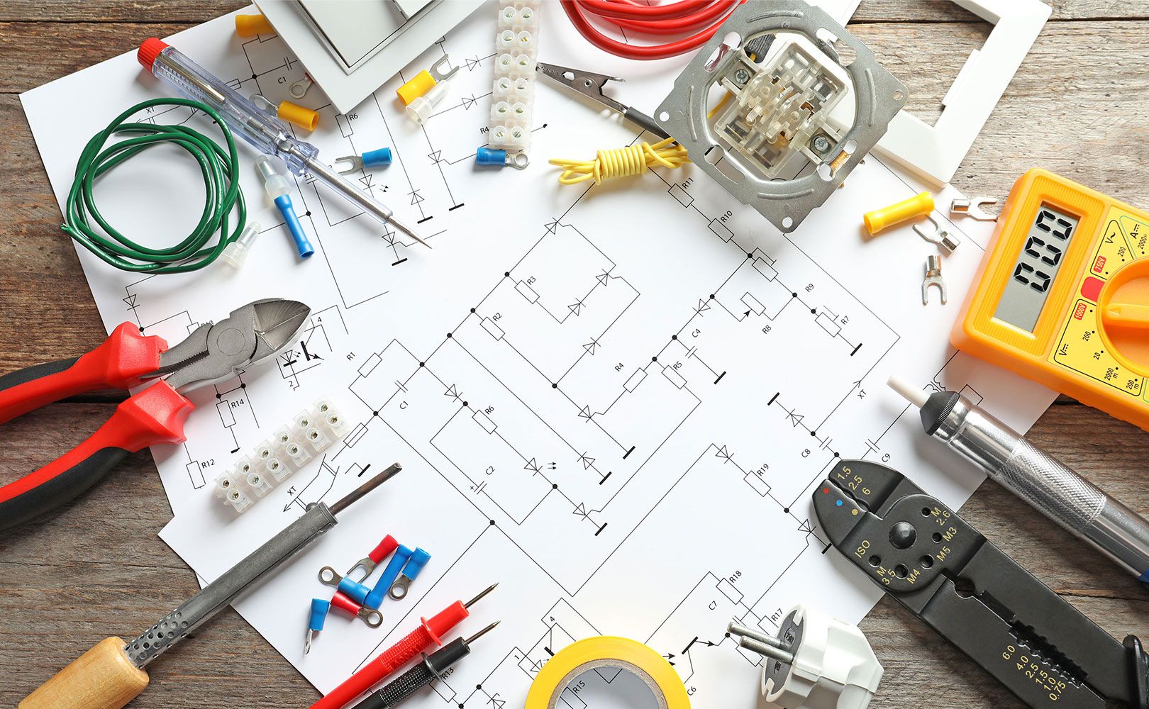 Elektrowerkzeuge, Kabel, Steckverbinder und ein Multimeter liegen auf einem Schaltplan